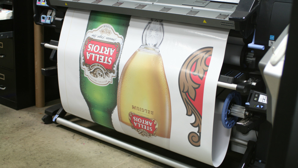 Large-format printer mid-run producing Stella Artois graphics on the production floor